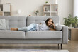 © fizkes - Lazy leisure time. Portrait cheerful preteen age girl lying on soft cozy sofa in comfortable pose head on hand at modern designed living room look at camera watch cartoons on tv enjoy carefree moment