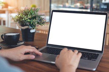 Mockup blank white screen laptop computer. Woman working, using laptop computer on wooden table with empty screen for advertising, template for web deign or social media marketing, freelance work