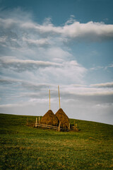 Rustic haystacks on a scenic rural hillside landscape with cloudy sky