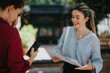 © qunica.com - Cheerful businesswoman having a conversation with a coworker outdoors, sharing documents and ideas under natural light.