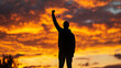 © Chalermrach - A man is standing in the sunset with his arms raised in the air
