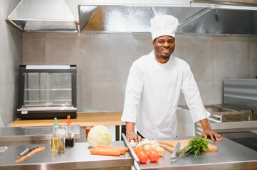 Portrait of happy African American male chef standing in restaurant kitchen