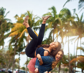 Wall Mural - Girl friends, laugh and carry game for adventure, travel and bonding together in Miami park. Freedom, playful and women with smile, happy and portrait on vacation for urban summer holiday or weekend