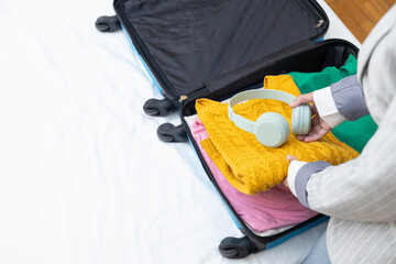 Close up Young business executive woman in hotel room taking vacation clothes out of suitcase on bed, trip in new city, resting in hotel room after long trip, business trips and work, blue suitcase