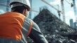 ©  lukaPixMedia - At a construction site, a worker in orange attire is captured in a back view, emphasizing the essential manual labor and dedication in modern urban development.