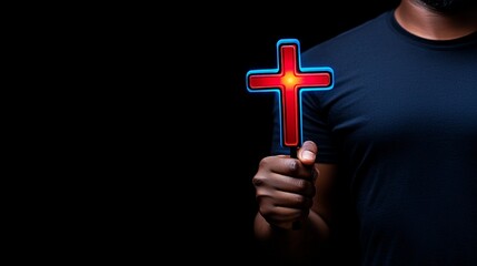 Faith Illuminated: A man's hand holds a glowing red cross against a dark backdrop, a powerful symbol of faith and hope. The image invites reflection.