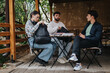 © qunica.com - Three college students sit together outdoors, engaged in a lively discussion after an exam, expressing relief and camaraderie.