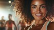 © Dulemegapixel - A woman with naturally curly hair displays a joyful and engaging expression during a fitness class, embracing an active and empowering lifestyle in an indoor setting.