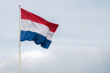 The flag of the Netherlands fluttering in the wind. Red, White and Blue. National pride and unity. The spirit of patriotism in Holland. Sky, water or buildings in the background.