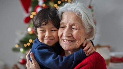 A joyful grandmother hugs her smiling grandchild in front of a Christmas tree, sharing a warm and loving holiday moment together.