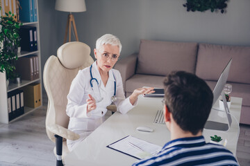 Poster - Photo of aged woman qualified doctor chatting patient wear white coat workplace office indoors