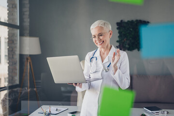 Poster - Photo of aged woman qualified doctor video call laptop wear white coat workplace office indoors