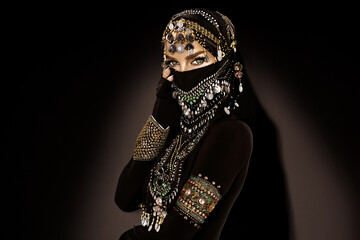 Portrait of an Arabian Princess. Beautiful Arabian woman portrait on black background. Young Hindu woman. Portrait of beauty Indian model who hiding her face behind the veil