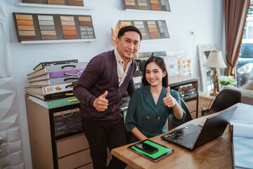 couple of asian interior shop crew looking at the camera with thumbs up while working at interior shop