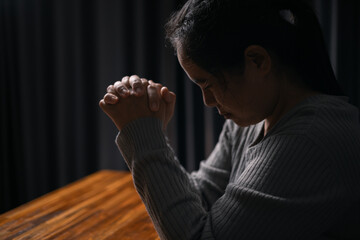 Wall Mural - Woman bowed her head in prayer, her hand clasped in faith, as she prayed to Jesus Christ for hope, peace, and the guiding presence of God in her religion. god, religion, faith, hope, peace, christian.