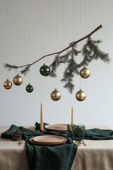 Wall Mural - Elegant holiday dining setup with gold ornaments hanging from a pine branch indoors