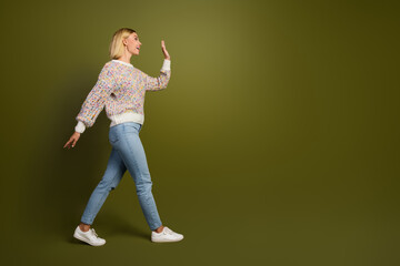 Joyful young woman in colorful sweater gesturing happily against khaki background, expressing positivity and style