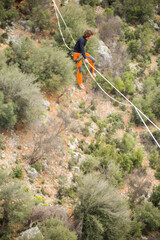 A tightrope walker walks along a cable stretched over a canyon.