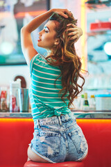 Fashion, vintage style and woman with back, confidence and relax in retro coffee shop. Gen z, cool girl and trendy model with color clothes and old school diner restaurant for creativity and art