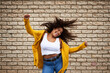 © Sanc/peopleimages.com - Excited, girl and dancing with hair flip for playful movement, energy and fun celebration of fashion winner. Happy, woman and rhythm for success, freedom and deal achievement on brick wall background