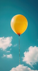 Bright yellow balloon floating serenely in the clear blue sky with fluffy white clouds on a sunny day