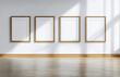 © Karat - A minimalist gallery wall featuring four blank picture frames with golden borders, set against a white wall. Sunlight and shadows play on the wooden floor, creating a serene and elegant atmosphere.