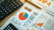 © Johannes - An overhead view of a desk with printed financial reports featuring pie charts and graphs, accompanied by a calculator and financial documents