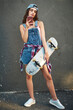 © CamPen2000/peopleimages.com - Woman, skateboard and smartphone with texting confidence and sports hobby on city gray wall. Gen z, cool and trendy girl with attitude, skater and edgy with positivity for creativity and holiday town