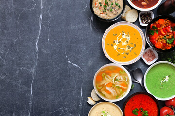 Poster - Assortment of delicious homemade soups. Above view side border on a dark slate background. Warm and cozy food concept.
