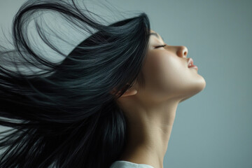 Woman with long black hair blowing in the wind, standing on a cliff overlooking the ocean at sunset.