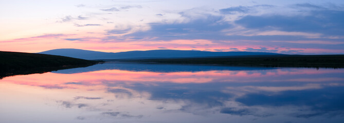 Poster - A beautiful sunset over a lake with a reflection of the sky in the water. The sky is a mix of pink and orange hues, creating a serene and peaceful atmosphere