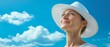 © Albert - A woman in a white hat gazes at the sky, surrounded by a blue backdrop dotted with white clouds