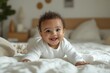 © Shahzad - Happy baby boy in a white onesie, lying on bed, joyful expression, close-up shot, blurred backdrop, stock photo, clear focus, copy space, bright tones, minimalistic feel, high quality image
