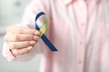 Sticker - Woman with yellow and blue ribbon on light background, closeup. Down syndrome awareness