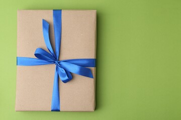 Poster - Gift box with blue bow on green background, top view. Space for text