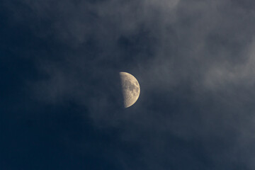 Wall Mural - half moon in the dark blue sky with clouds, close up.