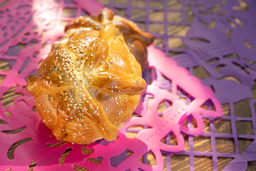 Two Pan de Muerto on Pink and Purple Papel Picado Background