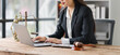 © Kritdanai - Focused Legal Professional: A female lawyer diligently works on her laptop in a professional setting, with a gavel and the scales of justice subtly visible in the foreground.