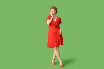 Wall Mural - Beautiful young woman in stylish red dress on green background