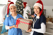 © Pixel-Shot - Female doctors in Santa hats with Christmas gift at hospital