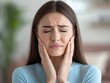 ©  Visual Pioneer - Young woman holding her face in discomfort, showing symptoms of facial pain or toothache, possibly indicating dental or jaw issues.