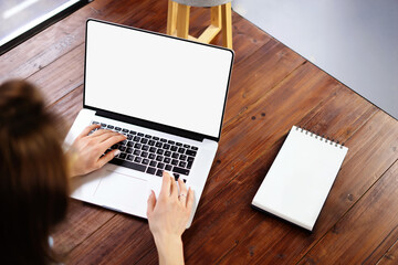 Mockup image of a woman using laptop with blank screen on wooden table