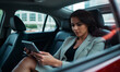 © Photo Builder - a businesswoman sitting comfortably in the back seat of a premium car working on her tablet