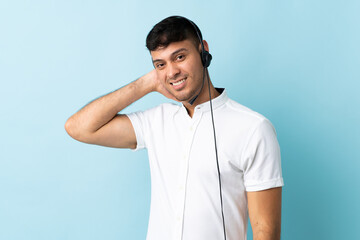 Telemarketer Colombian man working with a headset over isolated background laughing