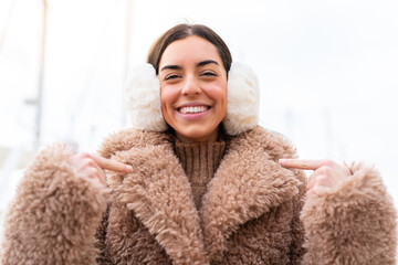 Young woman wearing winter muffs at outdoors with surprise facial expression