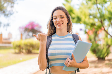 Canvas Print - Young pretty student woman at outdoors pointing to the side to present a product