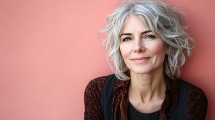 Western elderly woman dabbing eye cream under her eyes, smiling warmly at the camera, isolated on a pastel pink background Stock Photo with side copy space