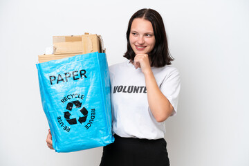 Young caucasian woman holding a recycling bag full of paper to recycle isolated on white background looking to the side and smiling