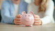 © enterdigital - A couple embraces their financial future, saving together with a cute pink piggy bank on a wooden table, symbolizing teamwork in finance.