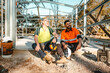 © Austockphoto - Construction workers sitting on the cemented floor on worksite, focus on foreground